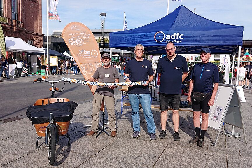 2025-09-20_Vier-inkl-Clemens.JPG Unsere Aktive vor dem Infostand, mit einer 1,5 m langen Schwimmnudel - diesen Abstand müssen Autofahrer innerorts beim Überholen von Radfahrenden einhalten