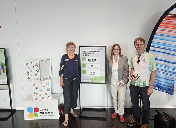 Siegerehrung des Stadtradelns Ingelheim mit Amelie Döres (ADFC RLP), Dr. Christiane Döll und Ulrich Reissner (beide Stadt Ingelheim), vor einer Tafel mit den erreichten Zielen des Stadtradelns